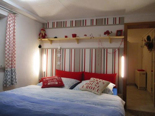 a bedroom with a bed with red pillows and a shelf at Ferienwohnung "Waldesruh" in Eibenstock