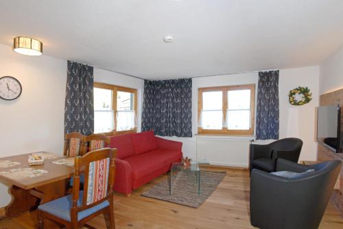 a living room with a red couch and a table at Der Berghof in Hirschegg
