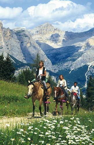 two people are riding horses on a mountain at Hotel Des Alpes in Selva di Val Gardena
