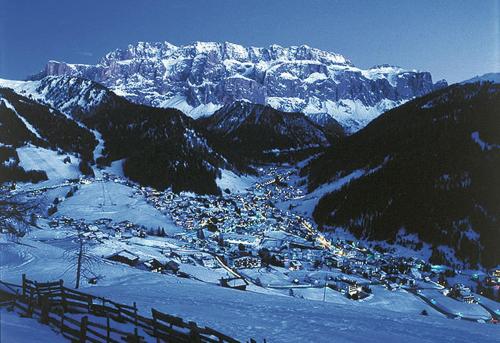a small town in the snow in front of a mountain at Hotel Des Alpes in Selva di Val Gardena