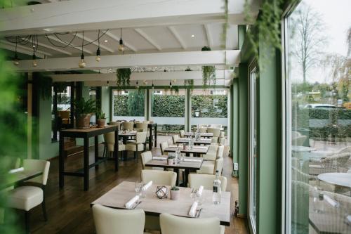 a restaurant with white tables and chairs and large windows at Hotel Restaurant de Sleutel in Riethoven