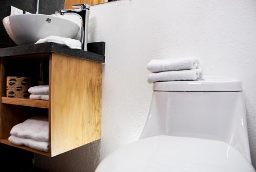 a bathroom with a toilet and a sink and towels at Romance City Hotel in Morelia
