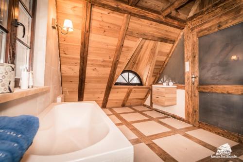 a bathroom with a white bath tub and wooden walls at Ranczo Pod Strzechą in Stara Kamienica