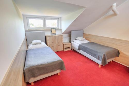 ポズナンにあるBotanik Hostelの赤いカーペットフロアのベッドルーム1室(ベッド2台付)