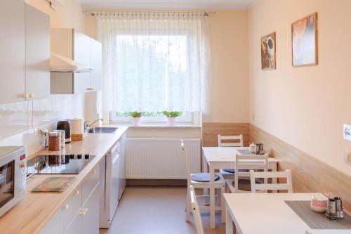 ポズナンにあるBotanik Hostelの白いキャビネット、テーブルと椅子付きのキッチンが備わります。