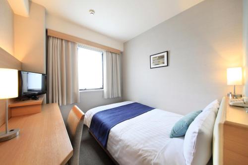 a hotel room with a bed and a television at Shonandai Daiichi Hotel Fujisawa Yokohama in Fujisawa