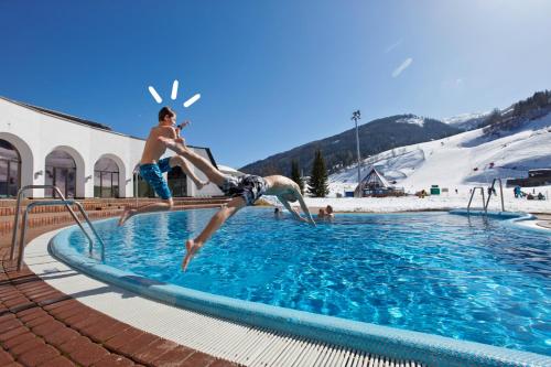 two young men jumping into a swimming pool at Gutzingerhof in Bad Kleinkirchheim