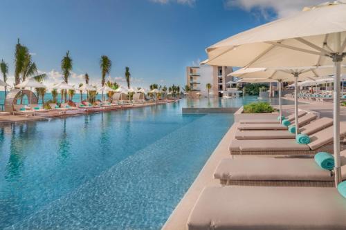 una piscina con tumbonas y sombrillas en Haven Riviera Cancun - All Inclusive - Adults Only en Cancún