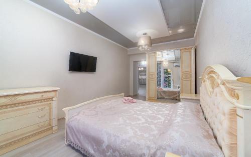 1 dormitorio con 1 cama y TV en la pared en Apartments Deribasovskaya, en Odessa