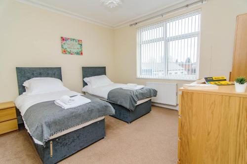 a bedroom with two beds and a desk and a window at Askern House in Doncaster