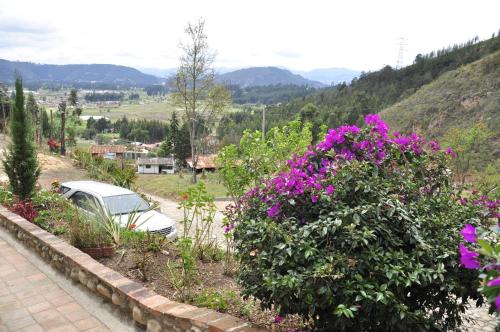 a car parked in a garden with purple flowers at Hotel Cabañas El Rincón de las Campanas in Nobsa