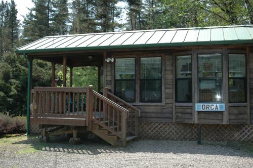 a large wooden cabin with a porch and a balcony at Park Motel and Cabins in Florence