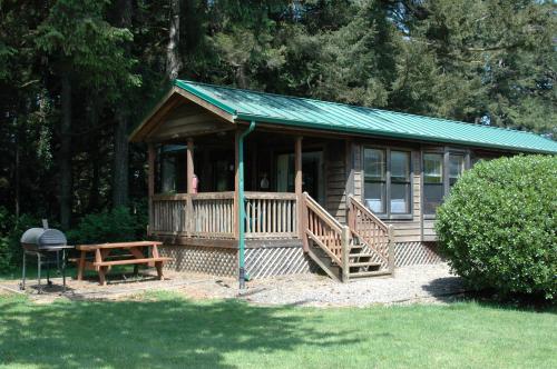 a small cabin with a green roof and a bench at Park Motel and Cabins in Florence