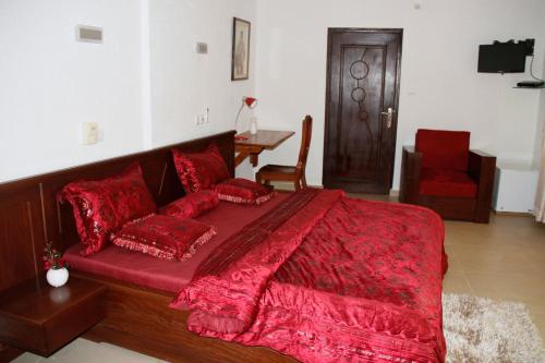 a bedroom with a large red bed with red pillows at Amazing Grace Residence in Cotonou
