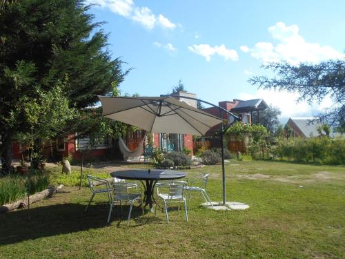 una mesa y sillas con una sombrilla en un patio en Cabañas La Maria Lourdes en Tafí del Valle