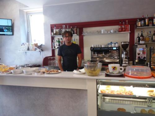 a man standing behind a counter in a kitchen at Affittacamere Il Borgo in Ceva