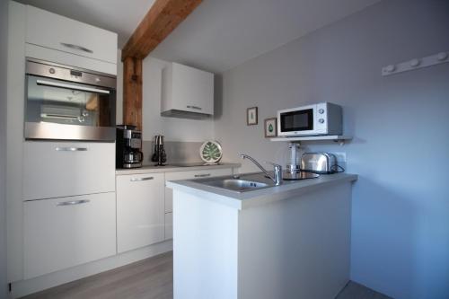 a white kitchen with a sink and a microwave at 1834&Spa Colmar in Colmar