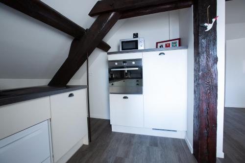 a kitchen with white cabinets and a microwave at 1834&Spa Colmar in Colmar