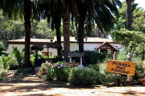 a sign in front of a house with a palm tree at Posada del Parque in Concón