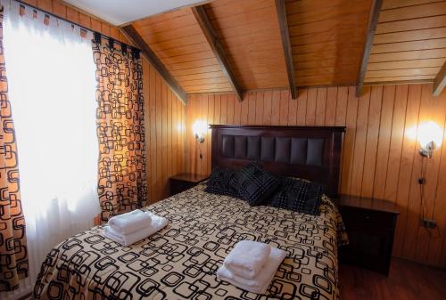 ein Schlafzimmer mit einem Bett mit zwei weißen Handtüchern darauf in der Unterkunft Cabañas Última Esperanza in Puerto Natales