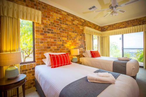 a bedroom with two beds and a brick wall at Aquila in Mount View