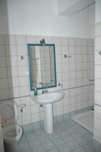 a bathroom with a sink and a toilet and a mirror at Studios Nikolaou Bros in Parga