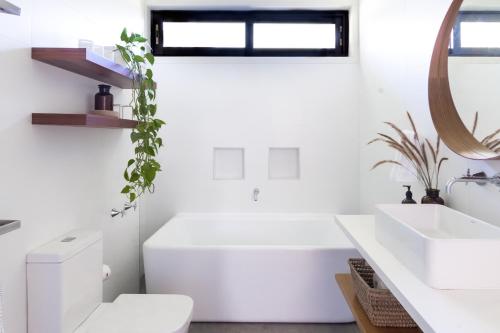 a bathroom with a white tub and a toilet and a sink at Dogwood in Pokolbin