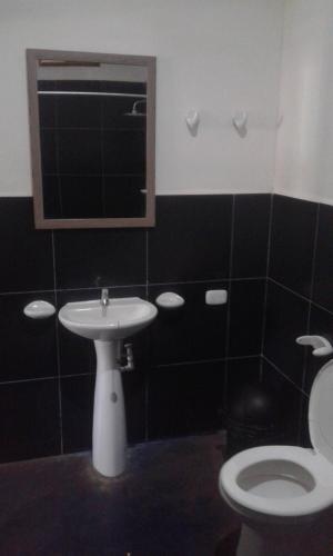 a bathroom with a white toilet and a sink at Badaboom Hostal & Surf in Aposentillo