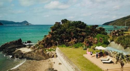 a view of a beach with people sitting on the grass at Holly Camp Airstream Villa Amami in Amami