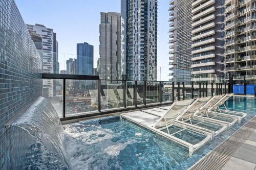 uma piscina no último piso com espreguiçadeiras num edifício em Shadow Play by Peppers em Melbourne
