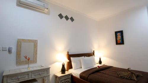 a bedroom with a bed and two lamps and a fireplace at Ayye Bungalows in Ubud