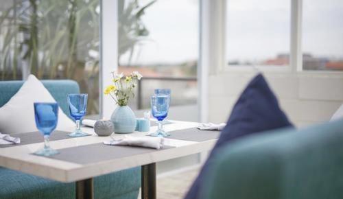 a table with blue glasses and a blue couch at de Vins Sky Hotel Seminyak in Seminyak