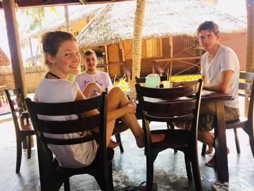a woman sitting at a table in a restaurant with two boys at Scoop Cabana Kitesurfing in Kalpitiya