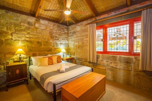 1 dormitorio con cama y pared de piedra en Monkey Place Country House, en Broke