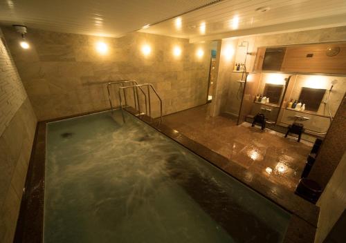 una gran piscina de agua en el baño con ducha en Hotel Claiton Esaka, en Suita