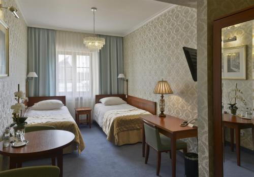 ein Hotelzimmer mit 2 Betten, einem Tisch und Stühlen in der Unterkunft Hotel Skala in Biała Podlaska