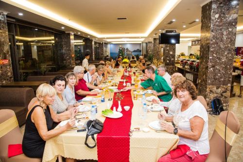 a group of people sitting at a long table in a restaurant at Sun Bay Tuan Chau Hotel in Ha Long