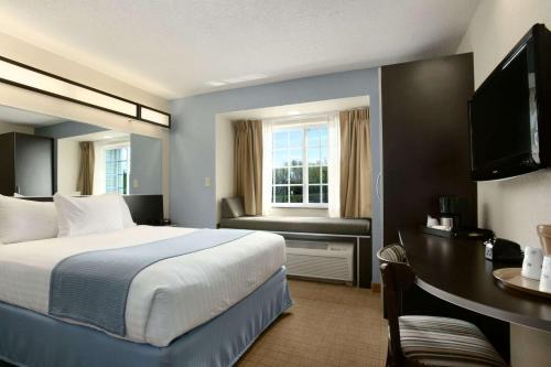 Habitación de hotel con cama, escritorio y TV. en Microtel Inn and Suites by Wyndham - Geneva, en Geneva