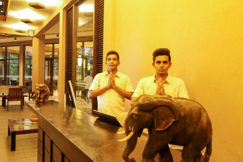 two men in ties standing next to a counter with an elephant at Oak Ray Wild Yala in Tissamaharama