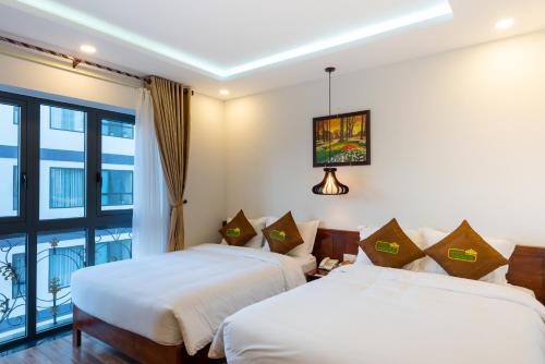 2 bedden in een kamer met een balkon bij HODI Hotel in Da Nang