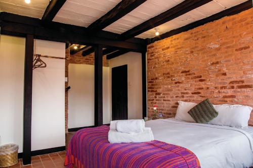 a bedroom with a bed and a brick wall at Lumbini Heritage Home in Pātan