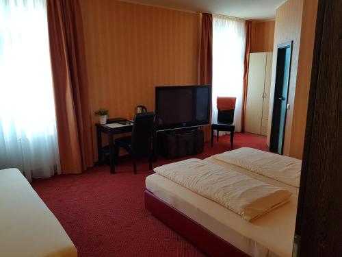 a hotel room with a bed and a desk and a television at Hotel Haupt in Kobern-Gondorf