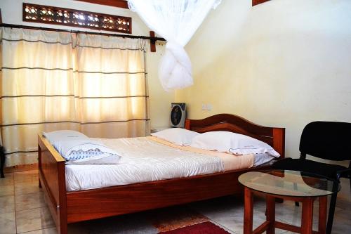 a bedroom with a bed and a chair and a window at Eco Resort Kasenyi in Entebbe
