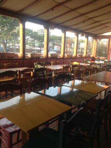 an empty restaurant with tables and chairs and windows at Alloggi Taverna Caorlina in Caorle
