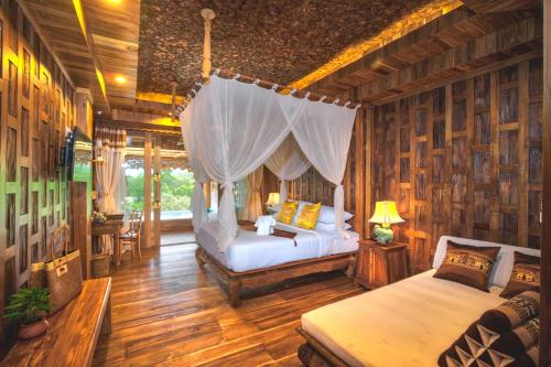 a bedroom with two beds in a room with wooden walls at Santhiya Tree Koh Chang Resort in Ko Chang