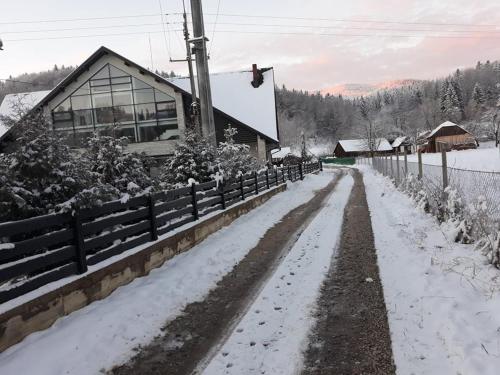 a snow covered road in front of a house at Pension Pîrîu' Morii in Gura Humorului