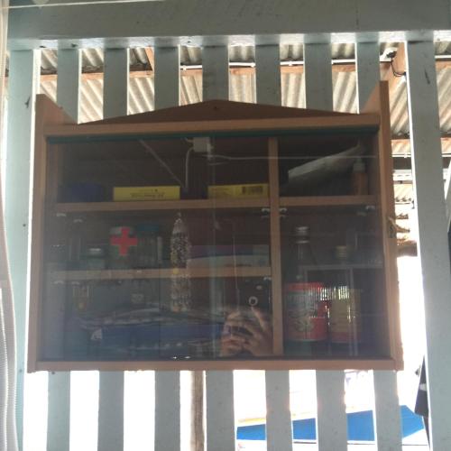 a wooden cabinet with a shelf with medicines on it at Rub Lom Chom Klong Homestay in Chumphon