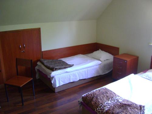 ein Schlafzimmer mit einem Bett, einer Kommode und einem Stuhl in der Unterkunft Hostel Promyk in Iwonicz-Zdrój