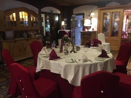 a dining room with a white table and red chairs at Feste Neustadt in Bergneustadt