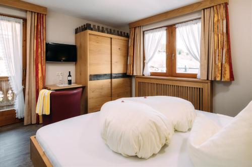 a bedroom with two beds and a desk and windows at Kinderhotel Laderhof in Ladis